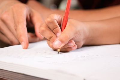 Child writing in a book with a pencil